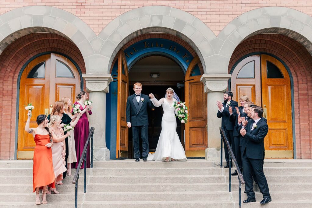 Bride & Groom exit their Catholic ceremony with their bridal party cheering for them at the Saint Thomas Church in Coeur d'Alene