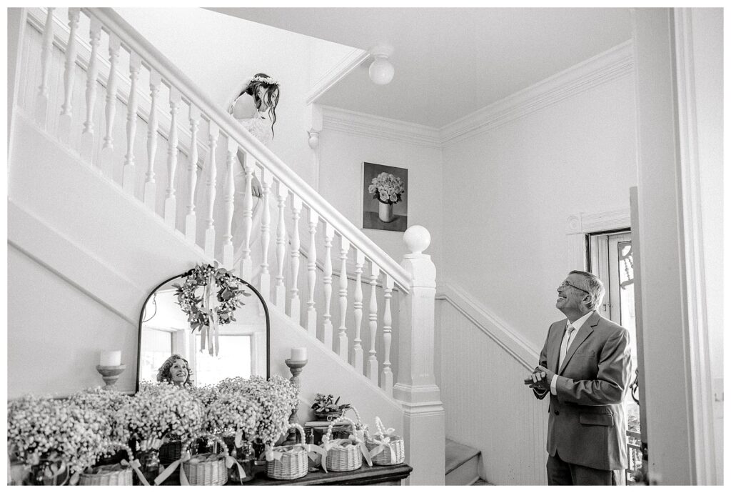 A black and white image of the first look with the Bride and her dad as she walks down the stairs of the Belle Gardens Wedding Venue Cottage