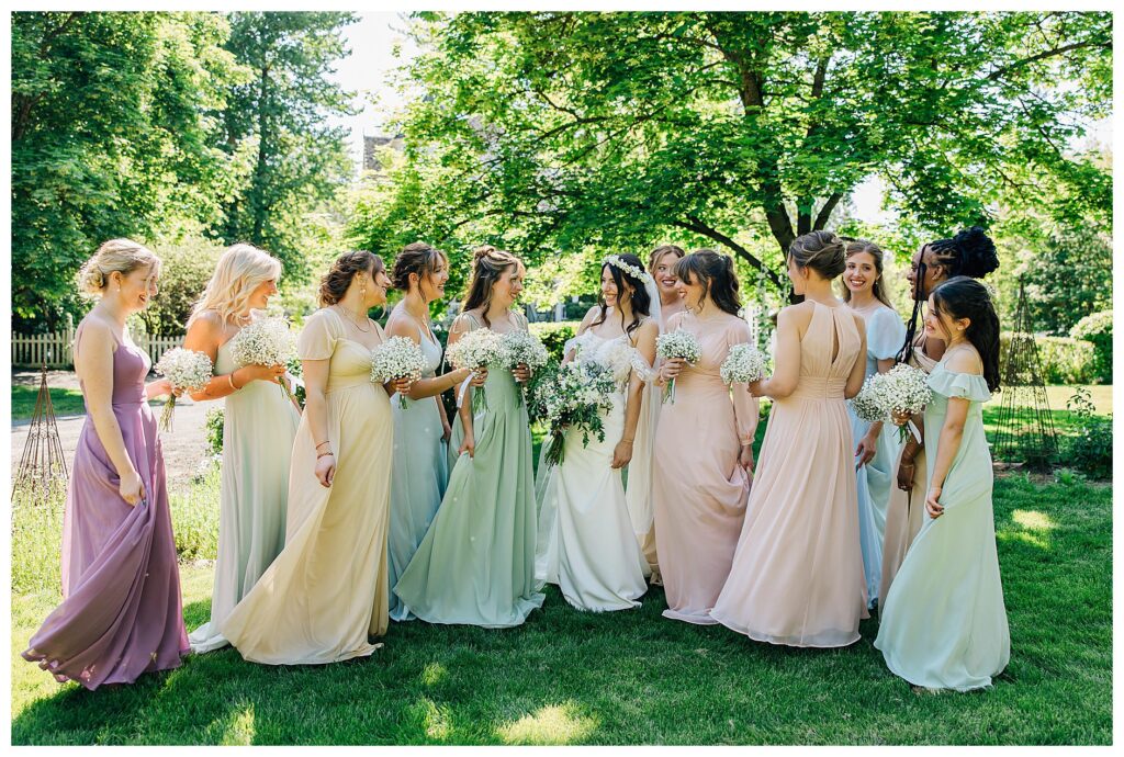 Bride and Bridesmaids twirling in their dresses of pastel spring colors of purple, blush, blue, yellow, and green 