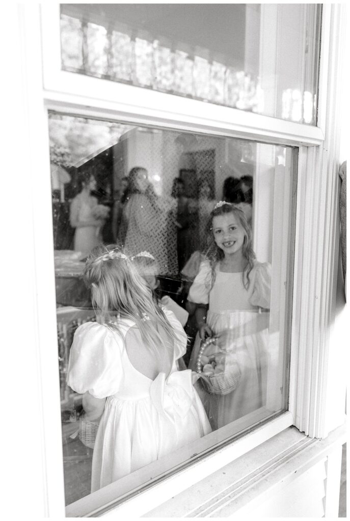 Flower girls looking through the window before the ceremony 