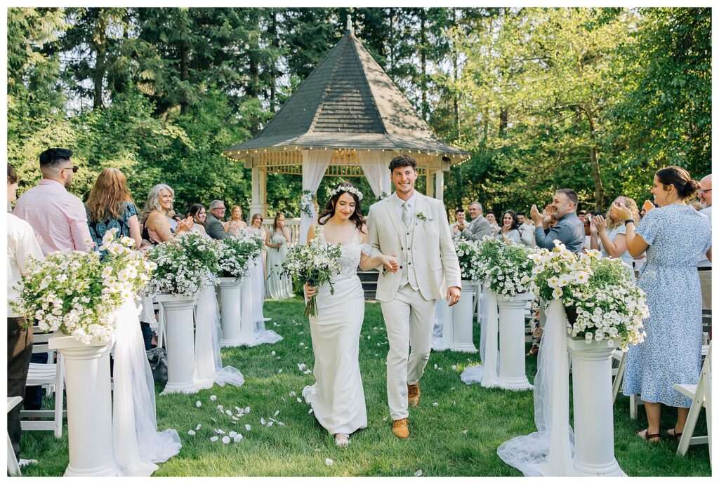 Bride and Groom smile as they walk back up the aisle after they got married at belle gardens 