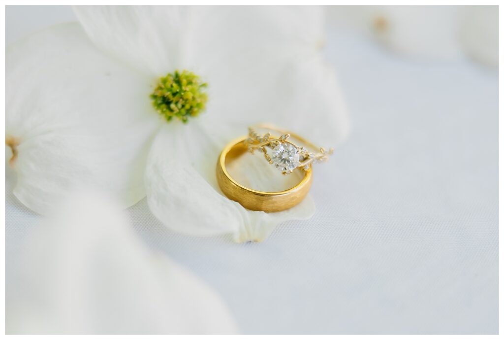 Antique Gold wedding bands laid among dogwood flowers picked from the Belle Gardens for a wedding detail photo